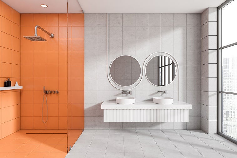 Baño moderno con azulejos naranjas y grises y lavabo doble flotante